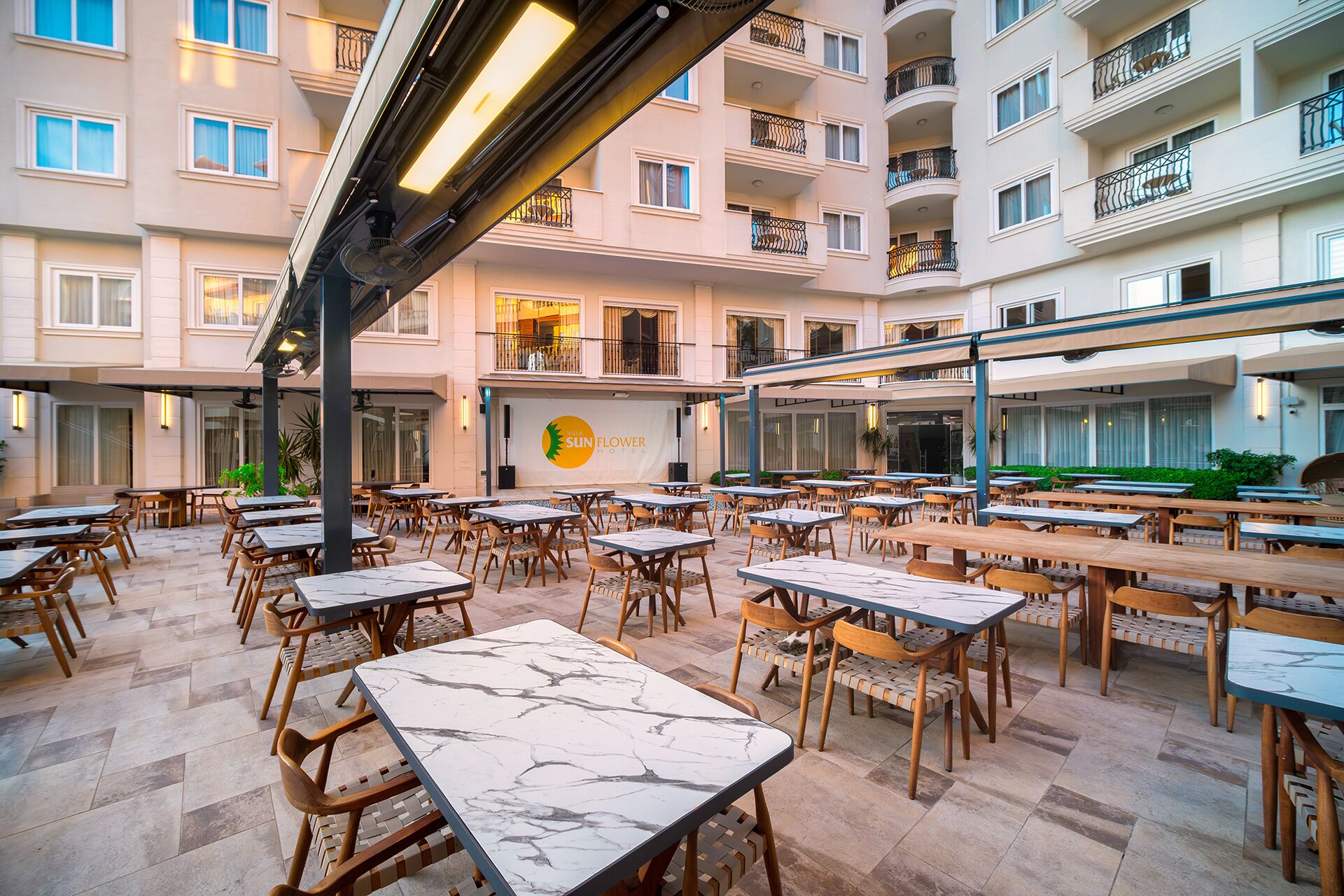 A hotel courtyard with outdoor seating, multiple floors, and a visible restaurant named "Sun Flower Hotel".