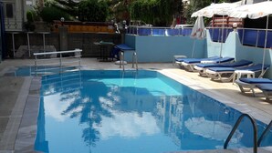 A swimming pool with blue water, a diving board, and lounge chairs. - Resitalya Hotel (Alanya)