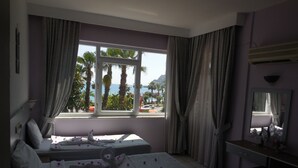 A hotel room with two beds, a large window with curtains, a desk, and a mirror. - Resitalya Hotel (Alanya)
