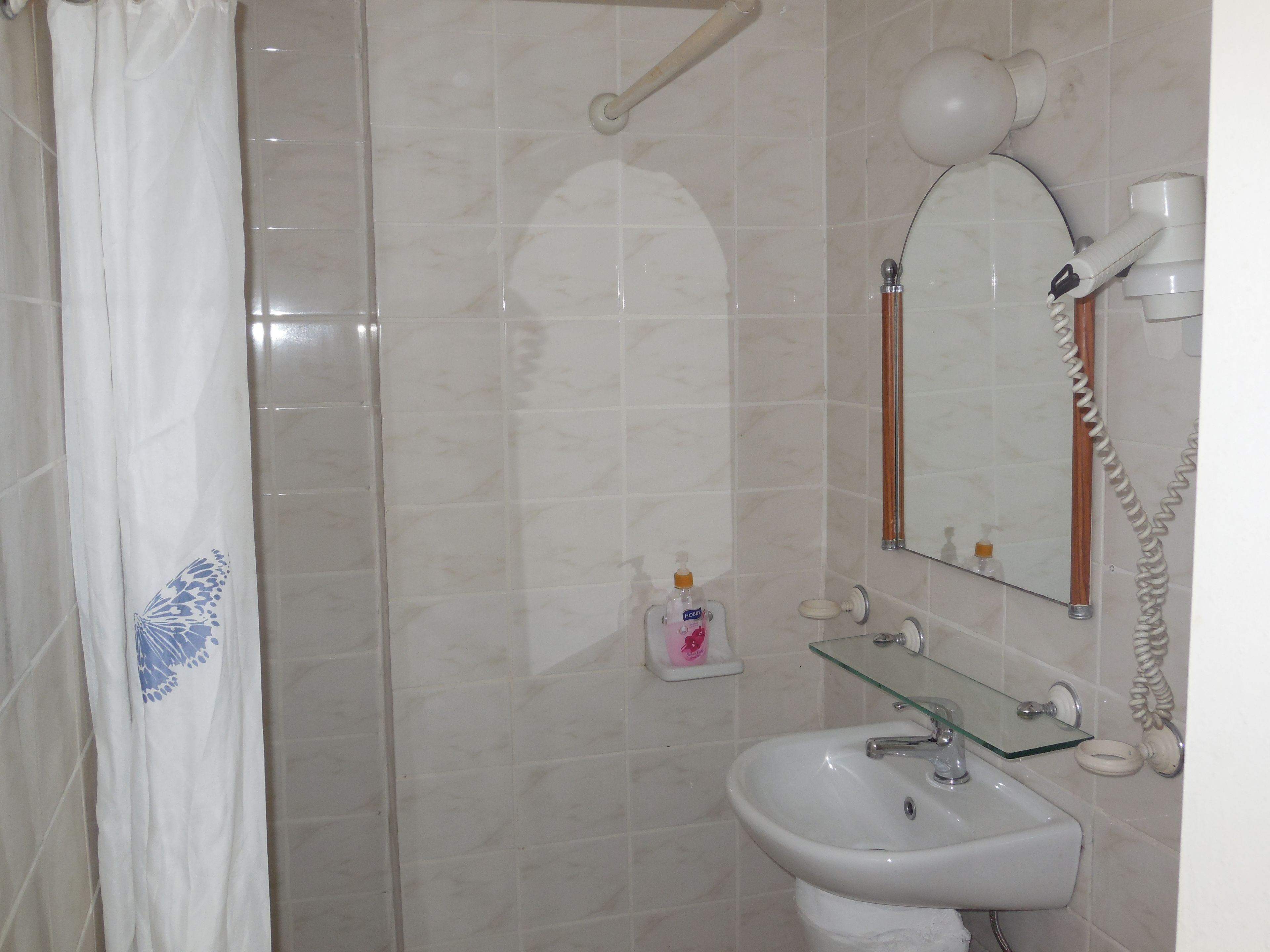 Een badkamer met een douche, wastafel, spiegel en telefoon.