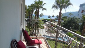 A balcony with red chairs, a view of the sea, and palm trees. - Resitalya Hotel (Alanya)