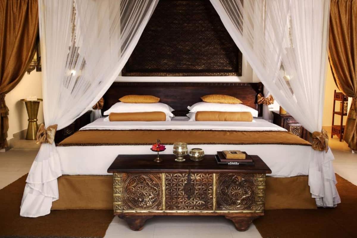 A bedroom with a large bed, ornate headboard, and a decorative console table.