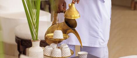 A person pouring a liquid from a brass container into a cup.