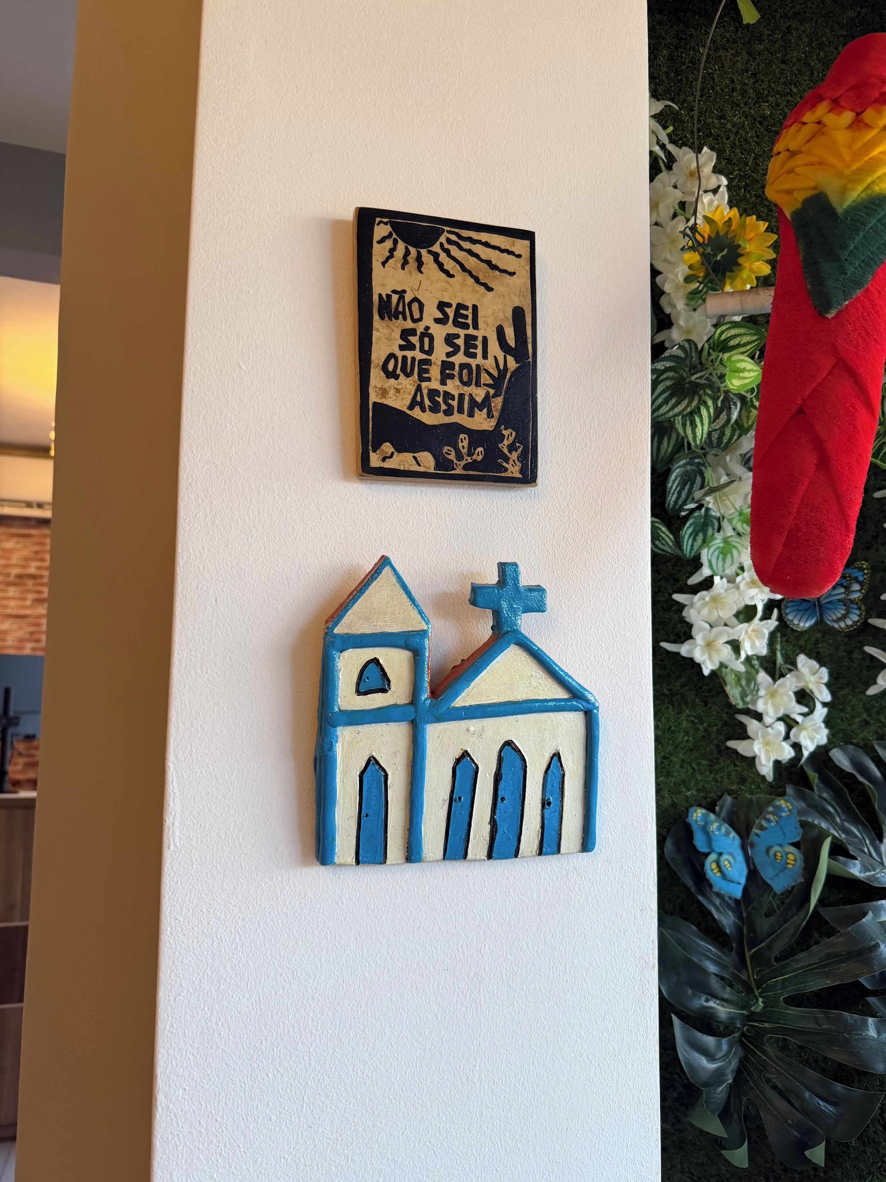A wall with a religious-themed decoration and a small blue and white building figure.