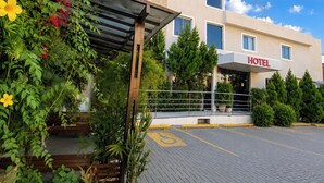 Een hotel met een overdekte ingang, een verhard parkeerterrein en een heldere lucht.