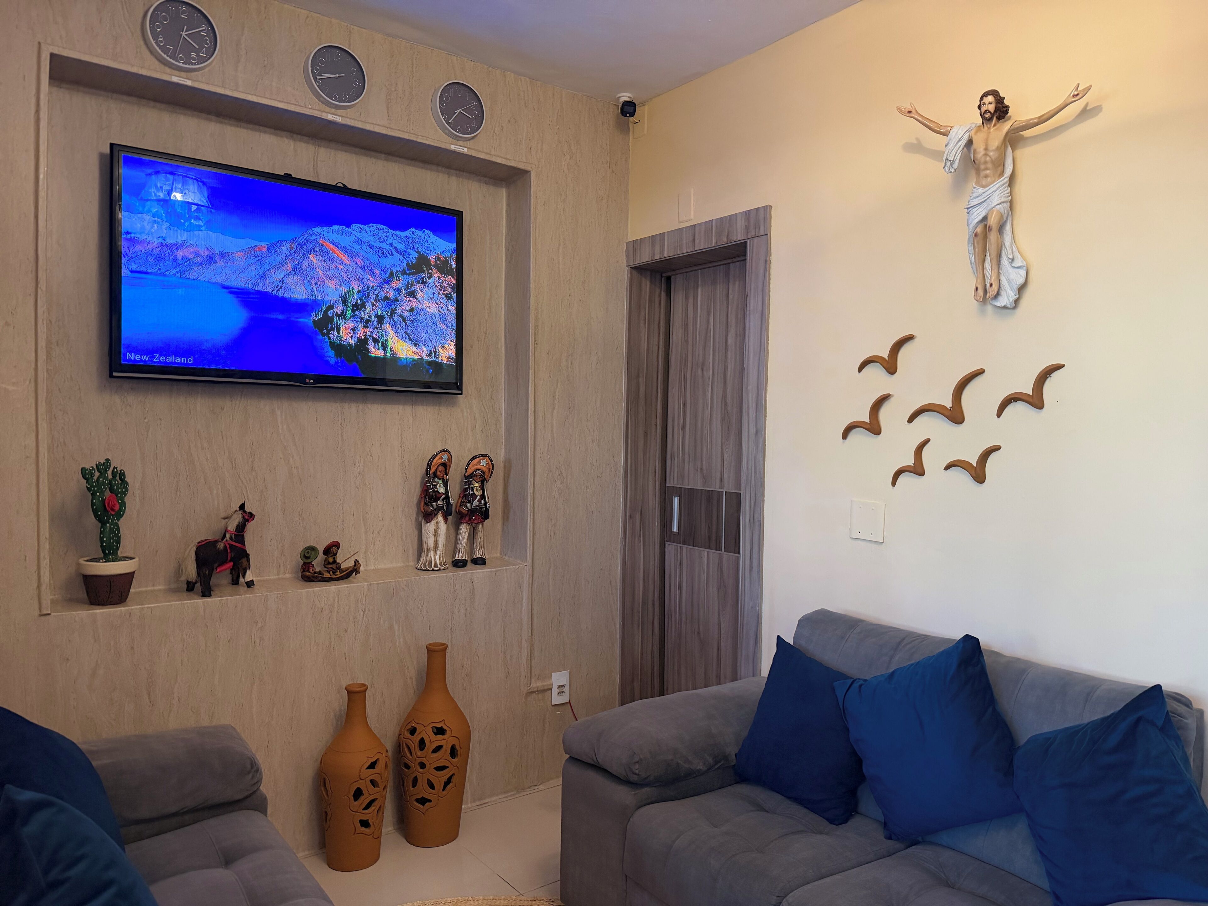 A living room with a flat-screen TV, decorative items, a couch, and a wall-mounted sculpture.