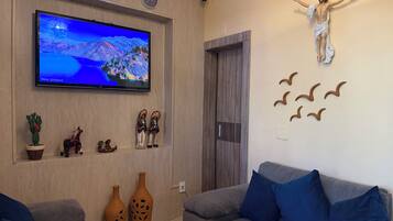 A living room with a flat-screen TV, decorative items, a couch, and a wall-mounted sculpture.