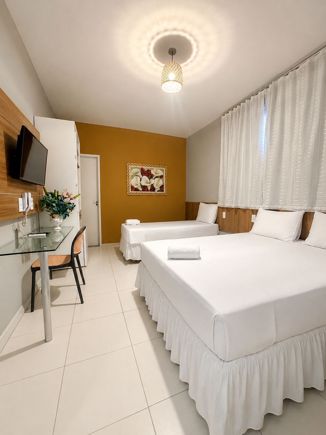 Habitació d'hotel amb dos llits, un escriptori amb cadira, una televisió i un quadre a la paret.