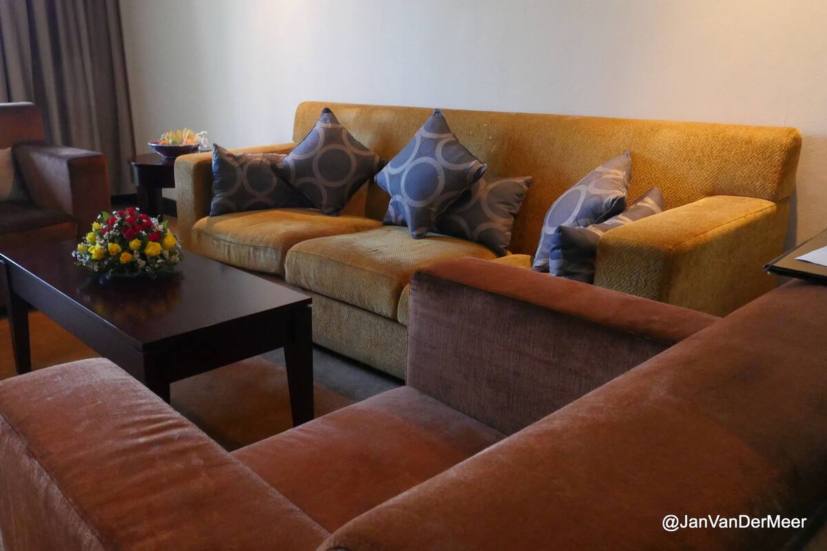 A living room with a sofa, armchairs, a coffee table, and a vase of flowers.