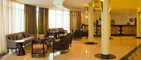 A lobby with a sofa, armchairs, a coffee table, and a reception desk.