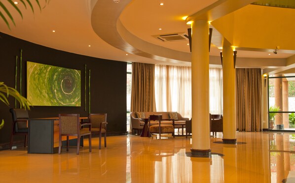 A spacious lobby with a large abstract painting, comfortable seating, and a polished floor.