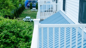 A residential deck with a blue roof, surrounded by greenery and a picnic table. - Seabreeze Motel (Old Orchard Beach)