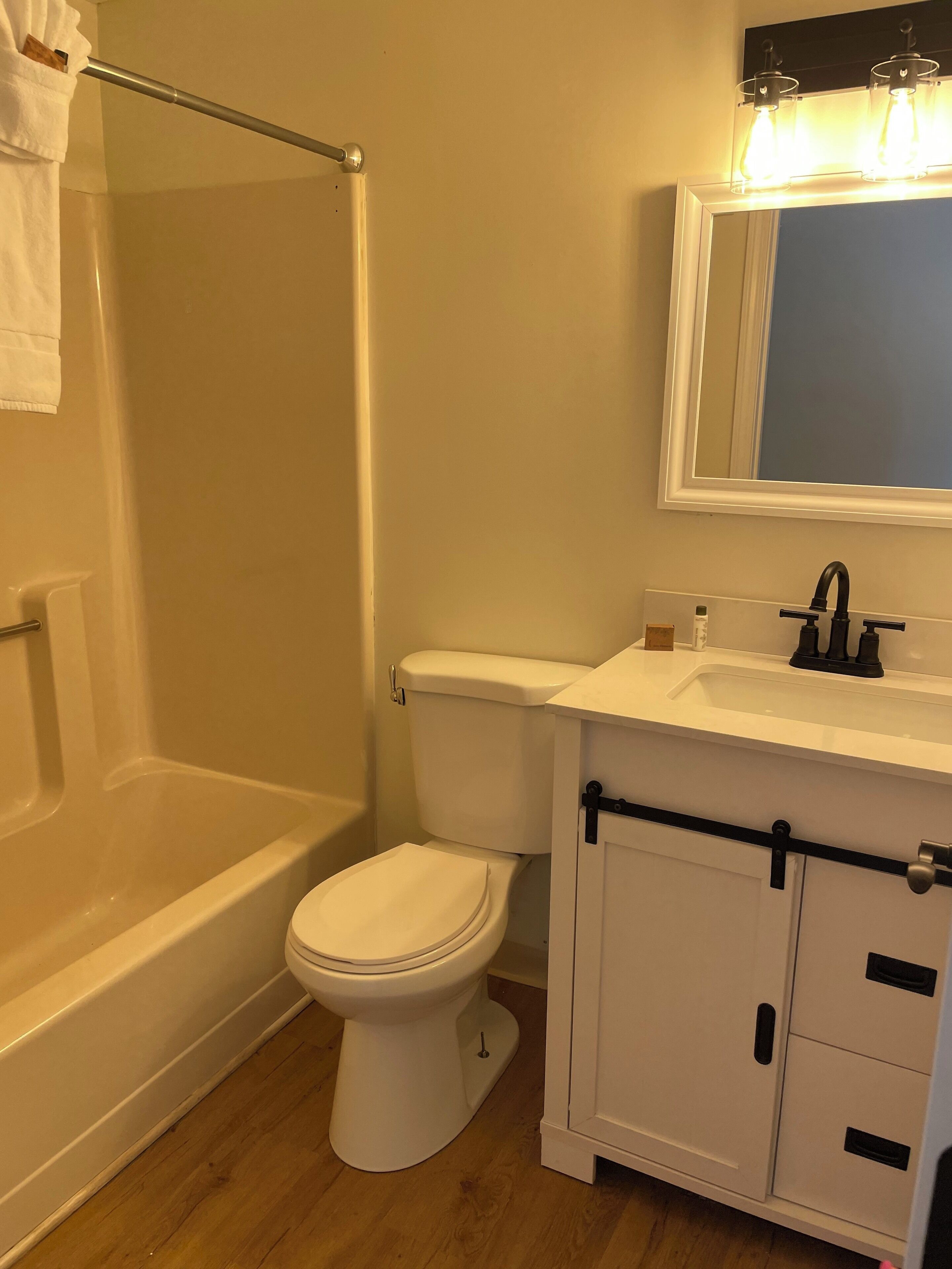 A bathroom with a bathtub, toilet, and a sink with a mirror above it.