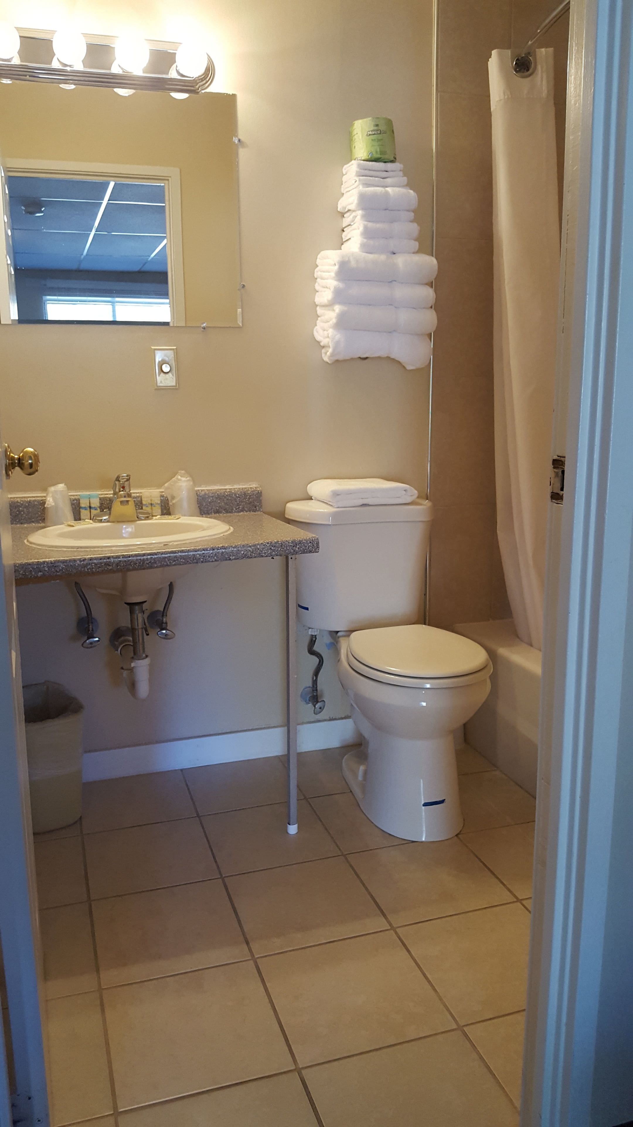Ein Badezimmer mit Waschbecken, Toilette und einem Stapel Handtüchern an der Wand.
