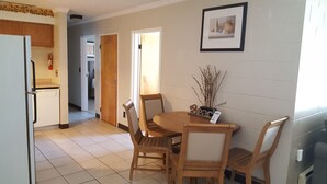 A kitchen with a refrigerator, a dining table with chairs, and a framed picture on the wall. - Seabreeze Motel (Old Orchard Beach)