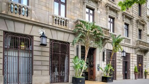 Um edifício histórico com portões de ferro ornamentados, grandes vasos de plantas e uma placa em formato de estrela acima da entrada.