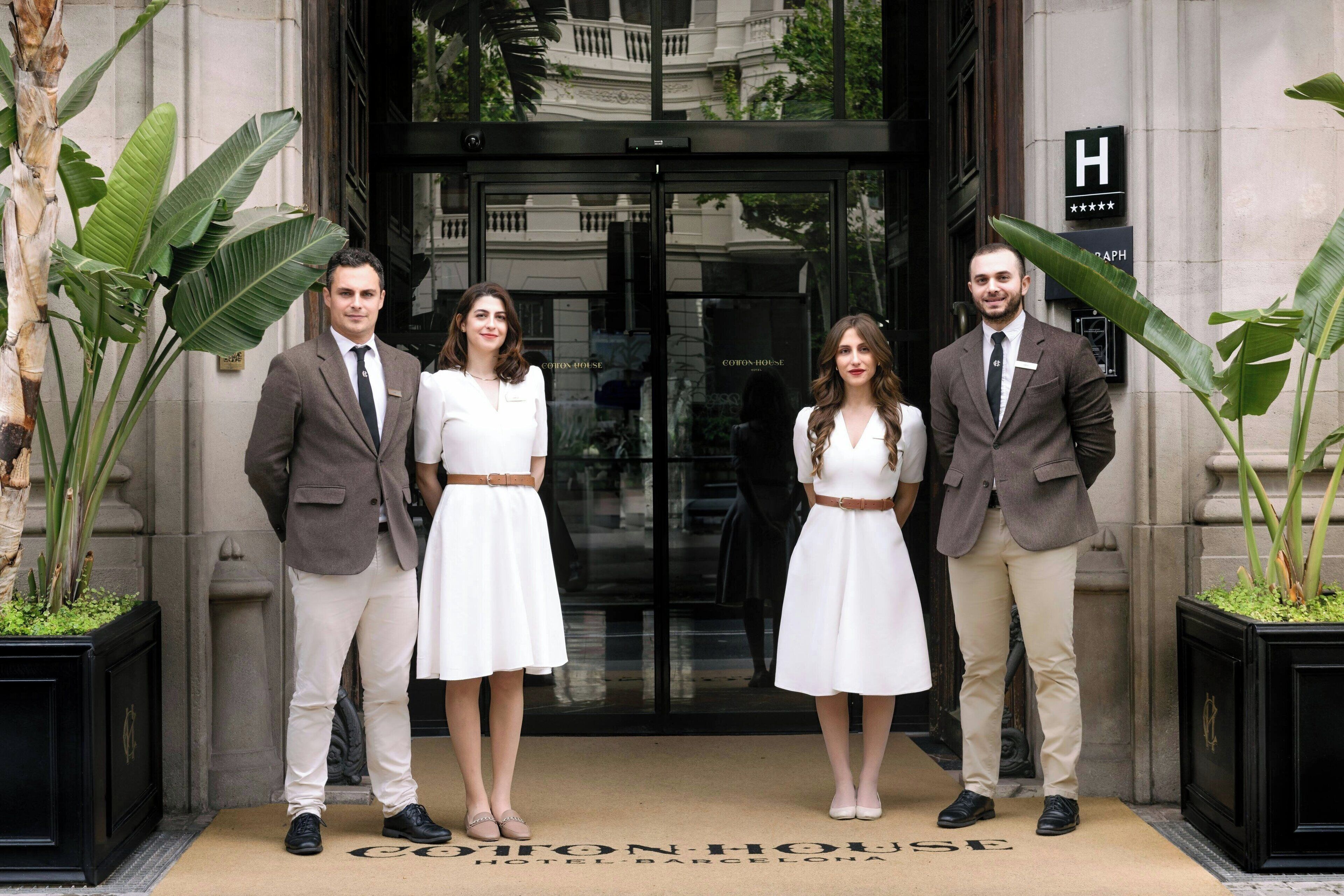 Cuatro personas de pie frente a la entrada de un hotel con un cartel que dice "Cohen House Hotel Barcelona".