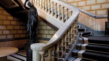 Una gran escalera con barandilla, una estatua y un candelabro.