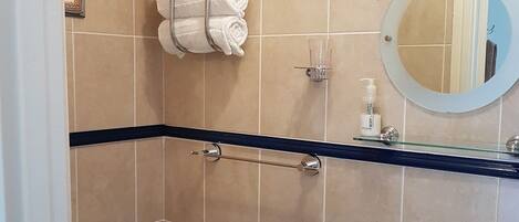A bathroom with beige tiles, a black countertop, a glass shower enclosure, a toilet, and a sink with a mirror.