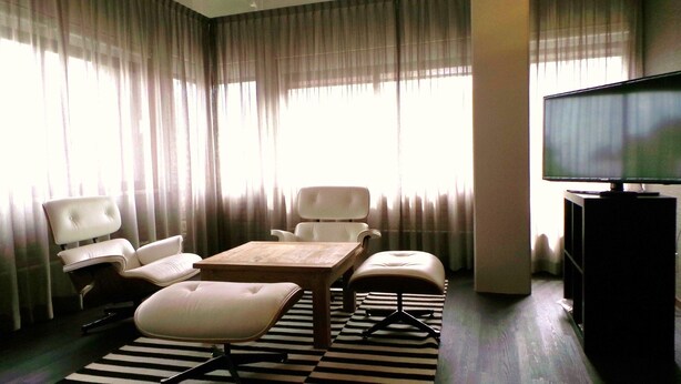 Una sala moderna con un sofá, dos sillones, una mesa de centro y un televisor.