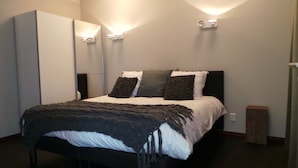 Un dormitorio moderno con cama, armario e iluminación empotrada.