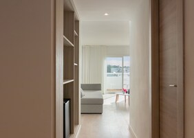 Una habitación de hotel moderna con balcón, un sofá gris y una mesita con un jarrón.