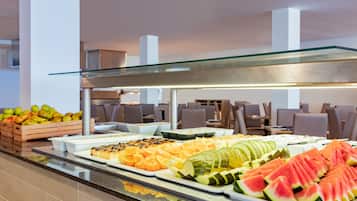 Ein reichhaltiges Buffet mit verschiedenen Früchten und eine Sitzgelegenheit mit Tischen und Stühlen.