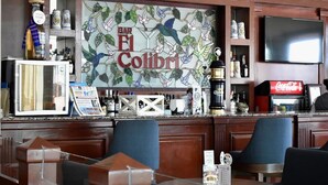 A bar area with wooden paneling, a Coca-Cola refrigerator, and a mural with birds and leaves. - Hotel Villa Florida Veracruz (Boca del Río)