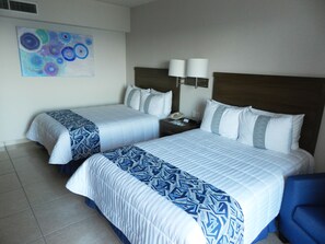 Two beds are flanked by pillows and a nightstand with a telephone and lamp.