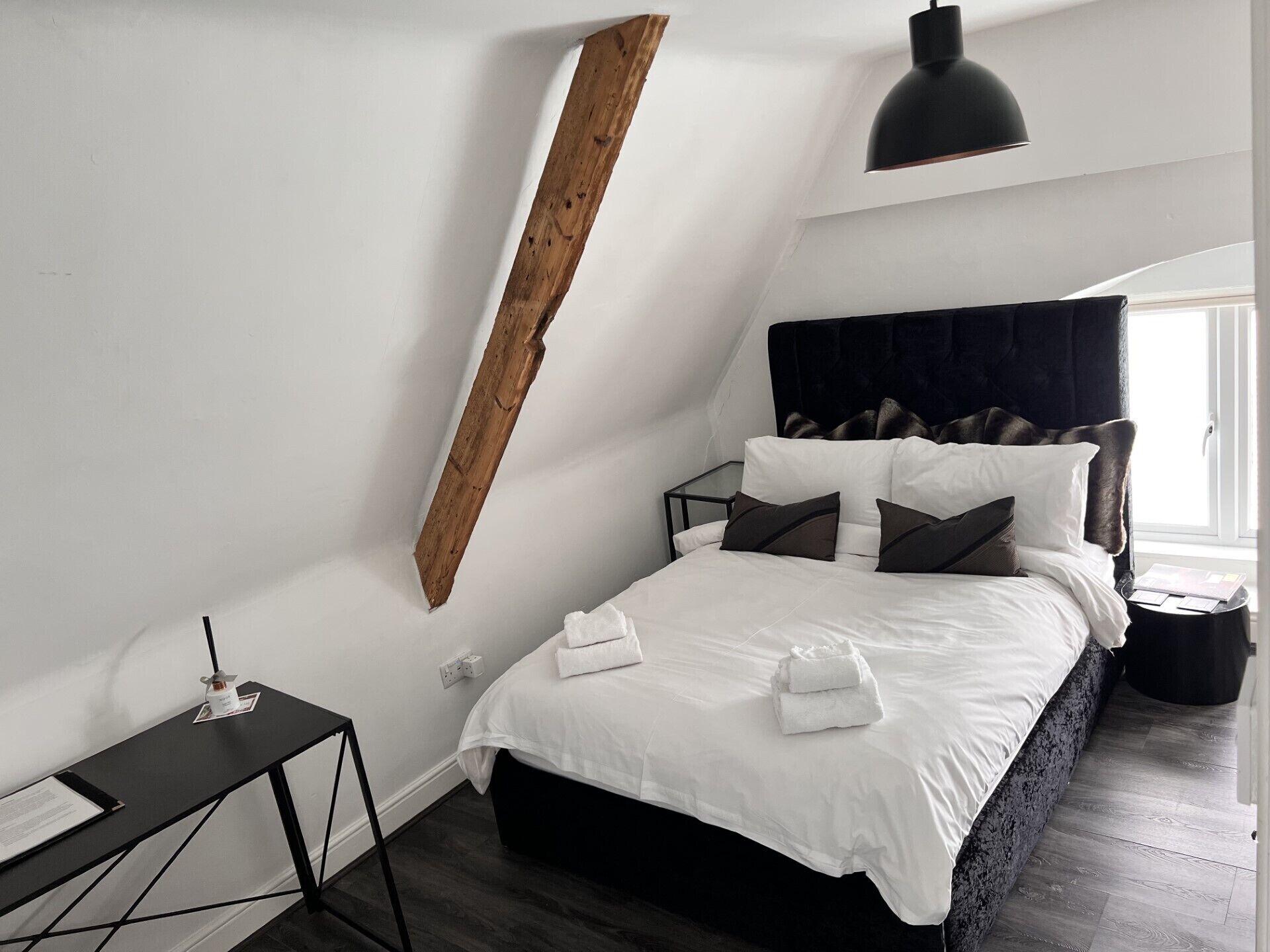 Una camera da letto con un letto, un comodino, una lampada e una finestra.