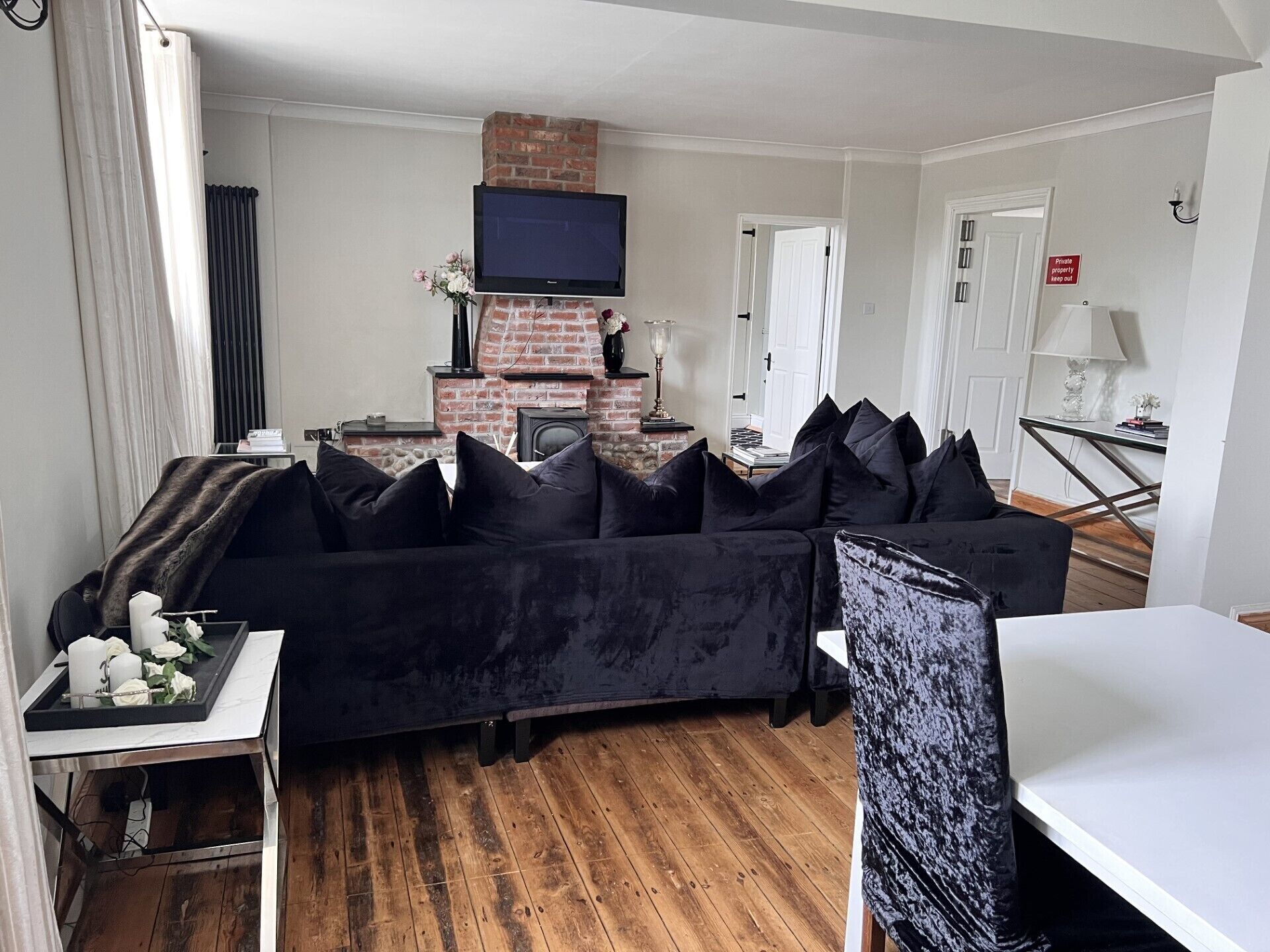 Un salon moderne avec un canapé noir, une cheminée et un téléviseur à écran plat.