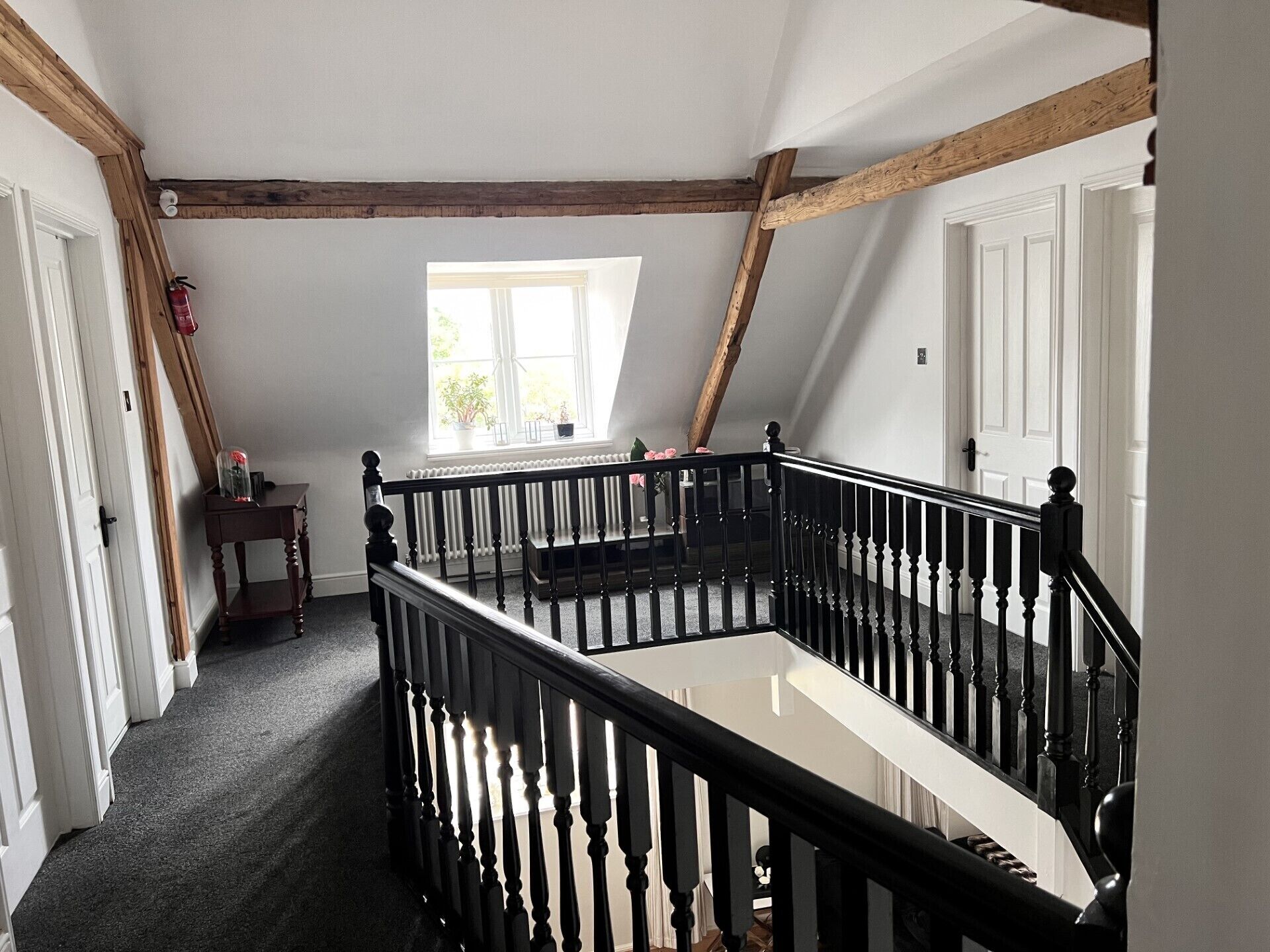 A staircase with black balusters, white walls, and exposed wooden beams.