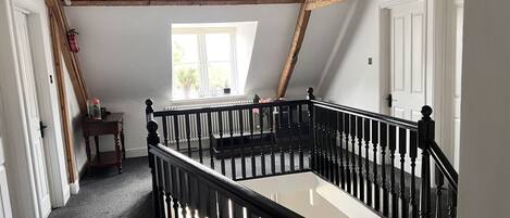 A staircase with black balusters, white walls, and exposed wooden beams.