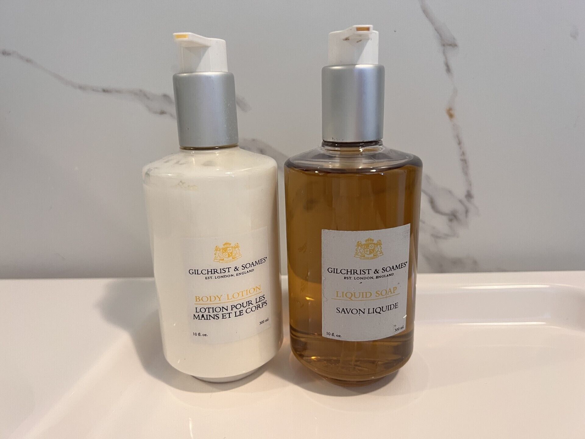 Two bottles of Gilchrist & Soames body lotion on a white surface.
