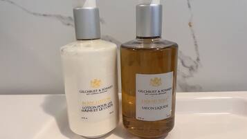 Two bottles of Gilchrist & Soames body lotion on a white surface.