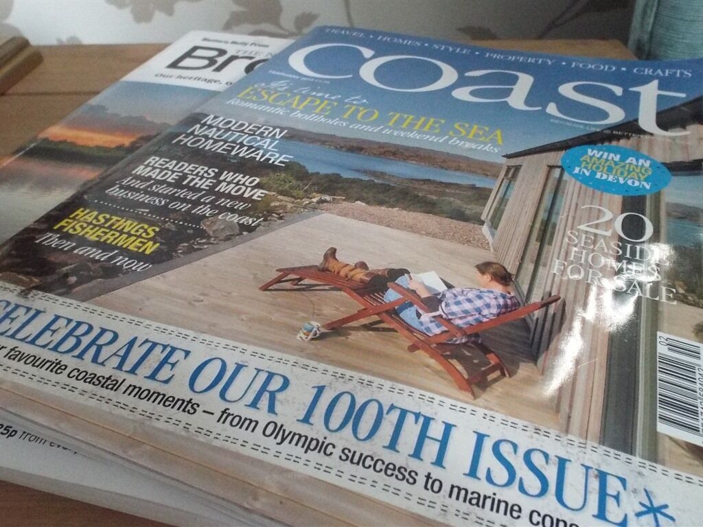 Portada de revista con una escena costera, una persona leyendo y texto sobre viviendas costeras y conservación marina.