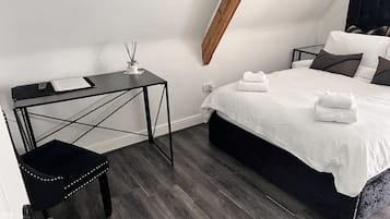 A modern bedroom with a bed, bedside tables, a desk, and a chair.
