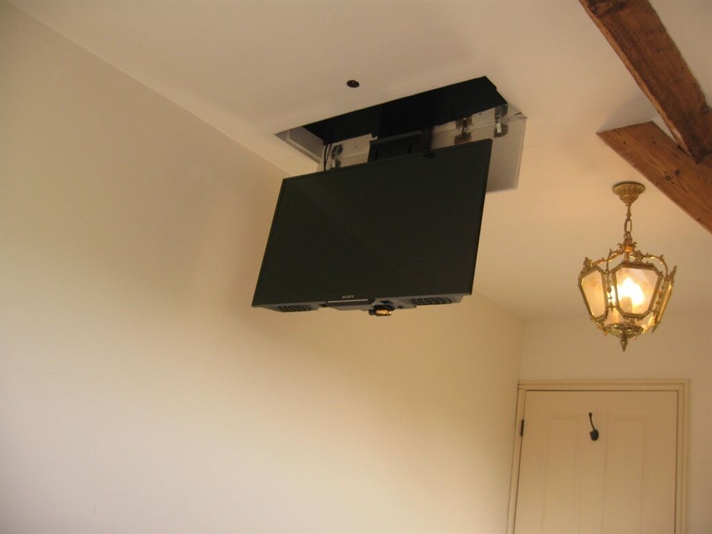 A room with a mounted flat-screen TV, a chandelier, and a door.