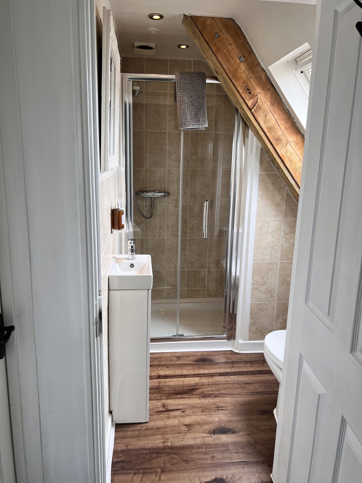Un bagno stretto con doccia, lavandino e WC.