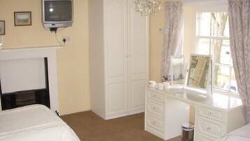 A bedroom with two beds, a dresser, a vanity, and a television.