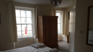 A bedroom with a bed, two windows, a wooden wardrobe, and a door leading to another room. - The Buck INN (Richmond)