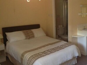 A hotel room with a bed, a nightstand, a bathroom with a sink and toilet.