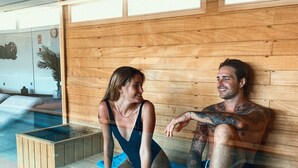 A wooden bench with a glass enclosure, a blue towel, and a wooden floor. - Lago Resort Menorca - Villas & Bungalows del Lago (Ciutadella de Menorca)