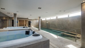 A spa area with two hot tubs, a pool, and a staircase leading to a shower area. - Lago Resort Menorca - Villas & Bungalows del Lago (Ciutadella de Menorca)
