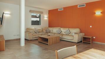 A modern living room with a beige sectional sofa, a wooden coffee table, and a dining table with chairs.