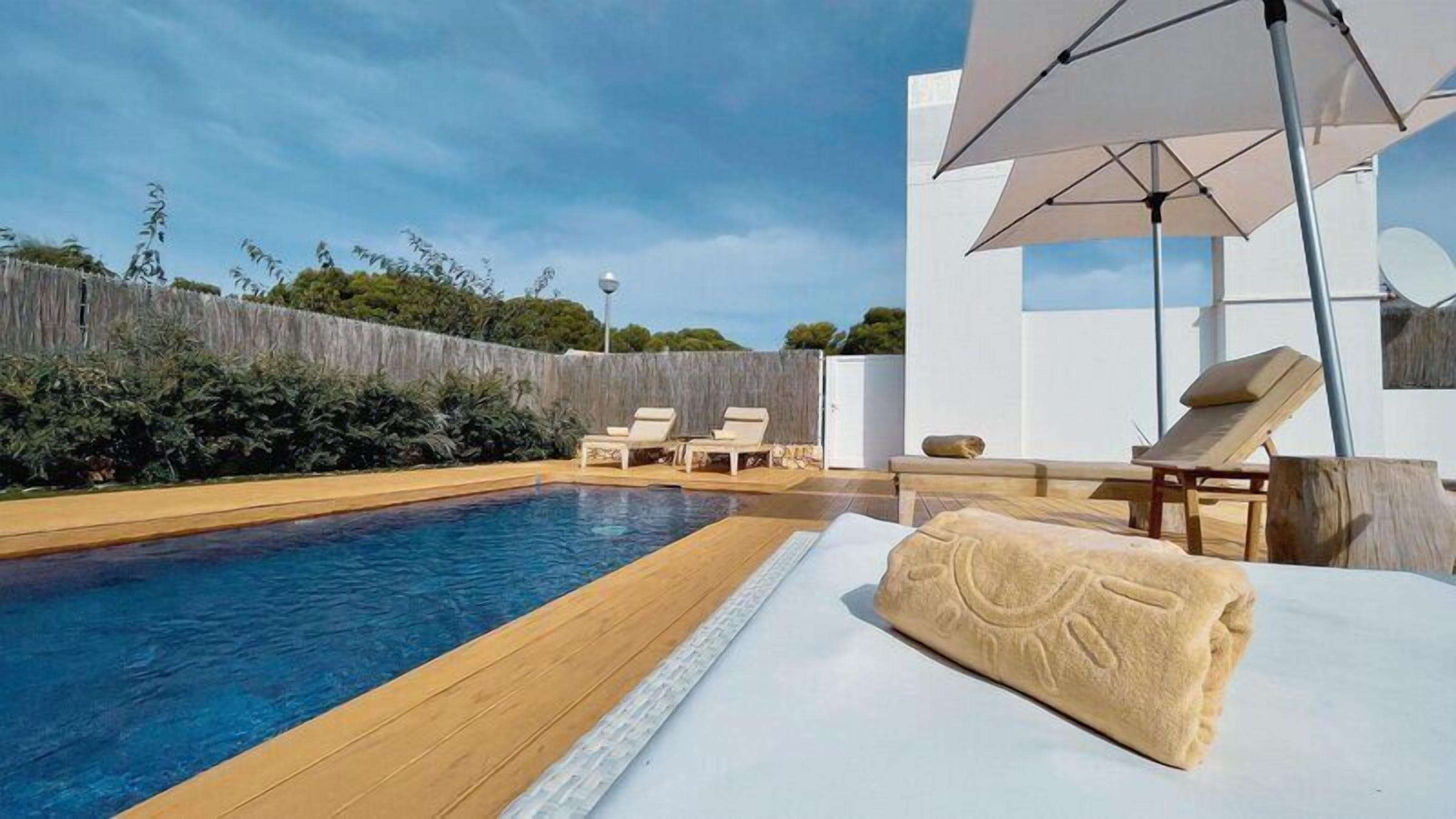 Una piscina al aire libre, sillones reclinables de piscina