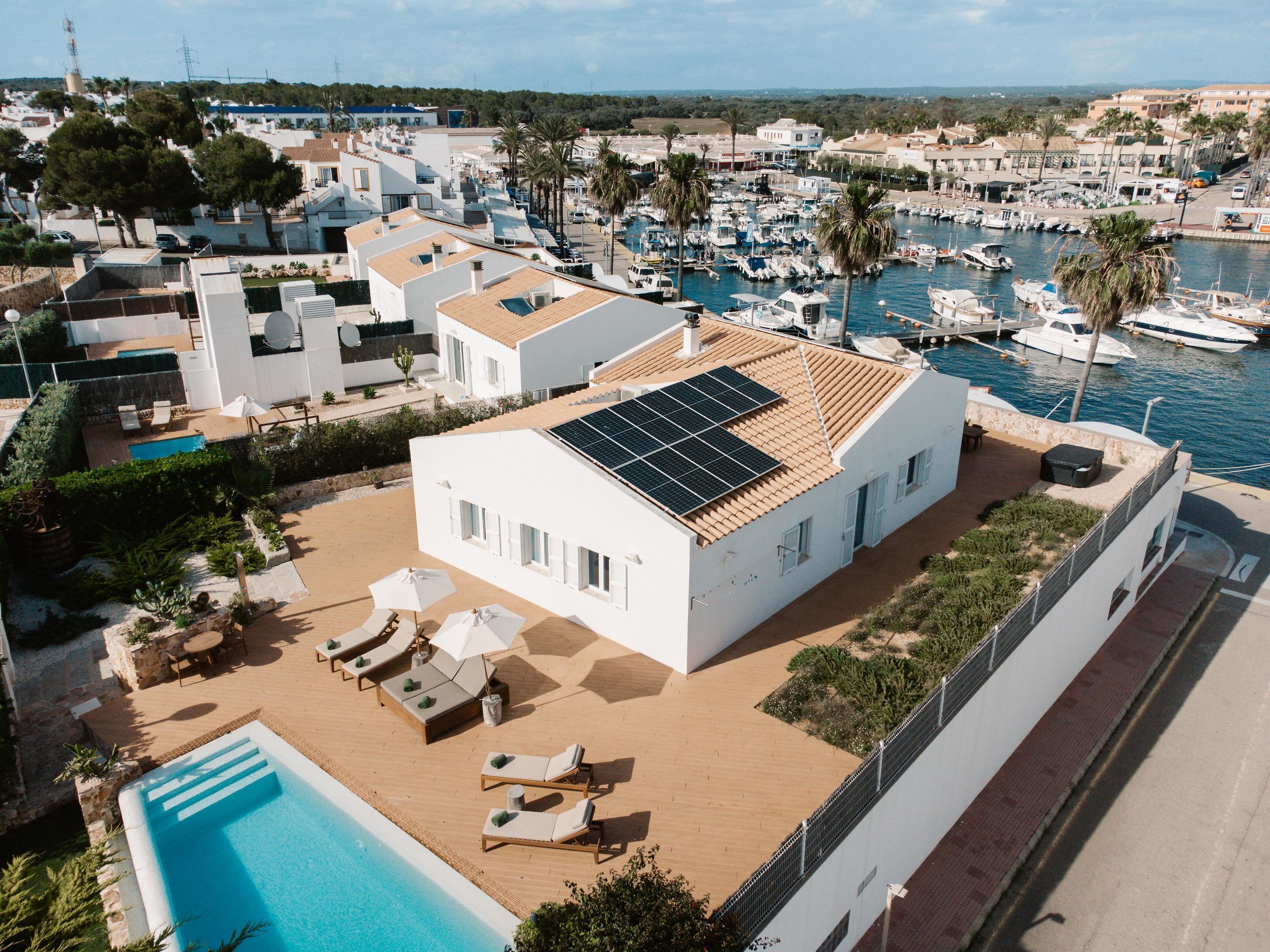 Una villa moderna con piscina en la azotea, paneles solares y vista al puerto deportivo.
