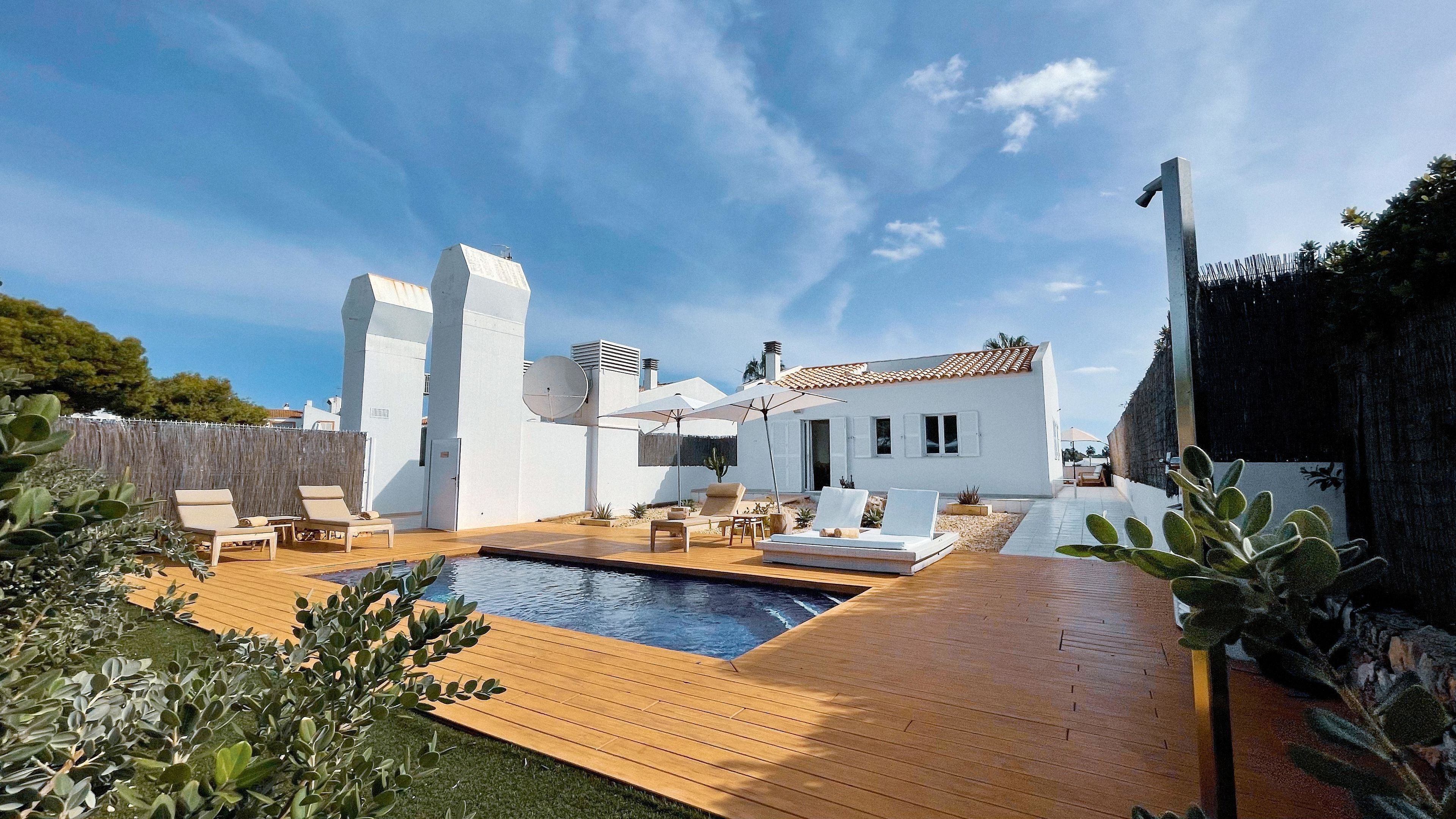 A modern villa with a swimming pool, outdoor seating, and a garden.