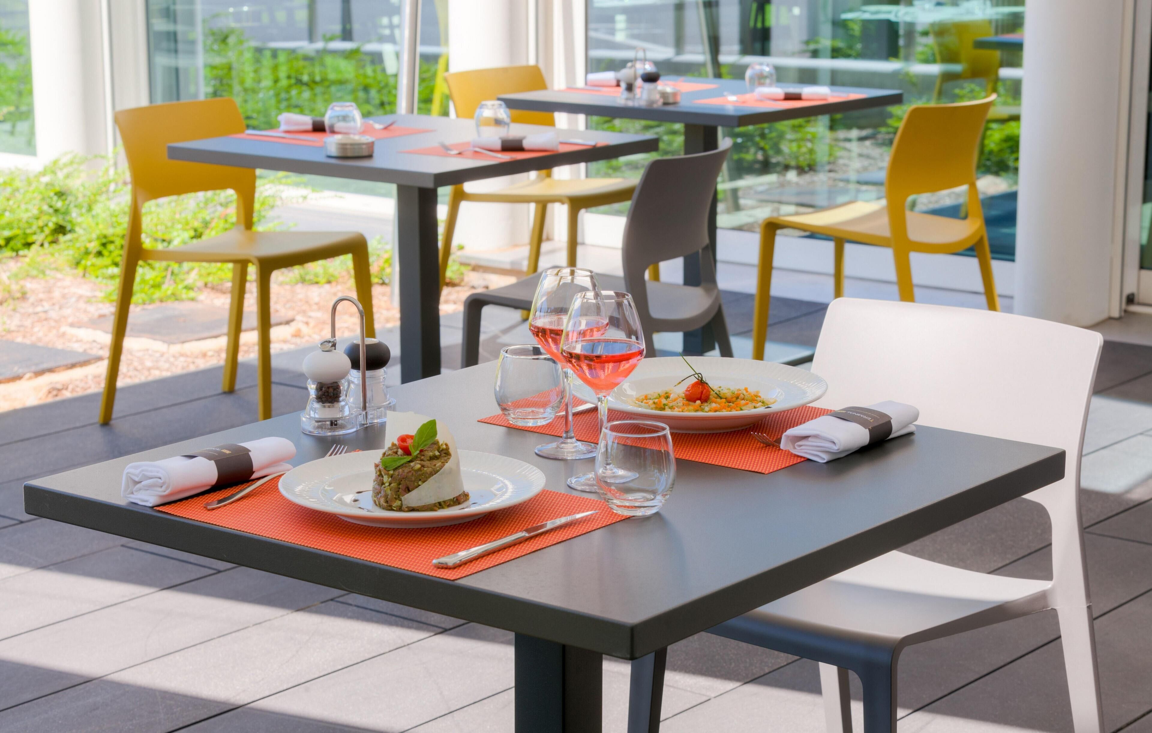 Comedor con mesas, sillas y vistas al exterior con vegetación.