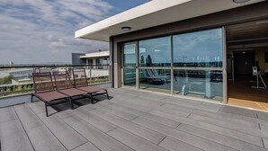 A modern building with a glass facade, outdoor seating area, and a view of the cityscape. - Spark by Hilton Lyon Eurexpo (Genas)